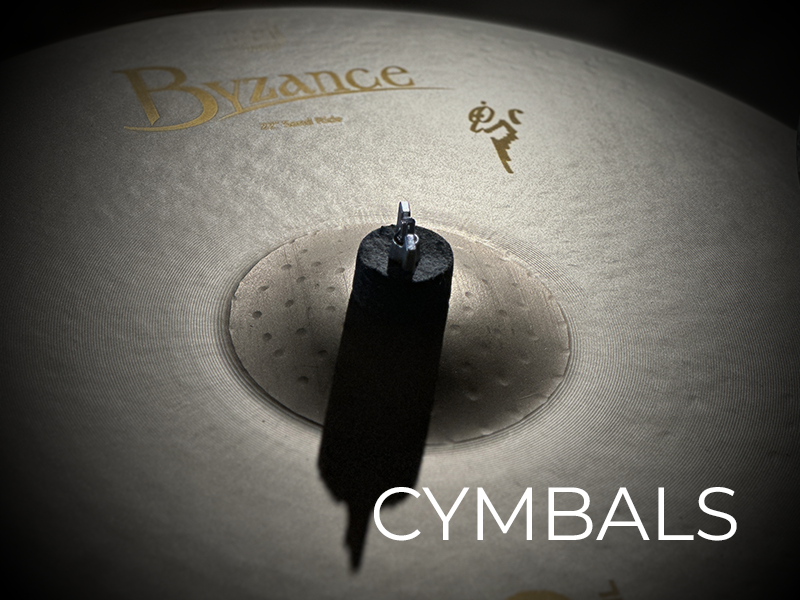 Close-up of a bronze cymbal with visible texture, mounting hardware, "Byzance" branding, and the word "CYMBALS" in white text at the bottom right.