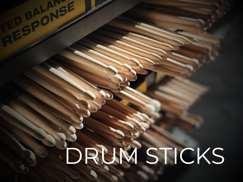 Multiple shelves filled with neatly stacked wooden drum sticks, with a "DRUM STICKS" label and partial signage reading "BALANCE RESPONSE" above.