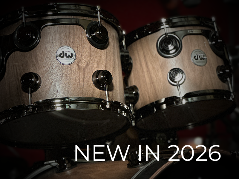 Close-up of two DW drums with a wood finish and dark hardware, featuring the text "NEW IN 2026" in bold white letters at the bottom.